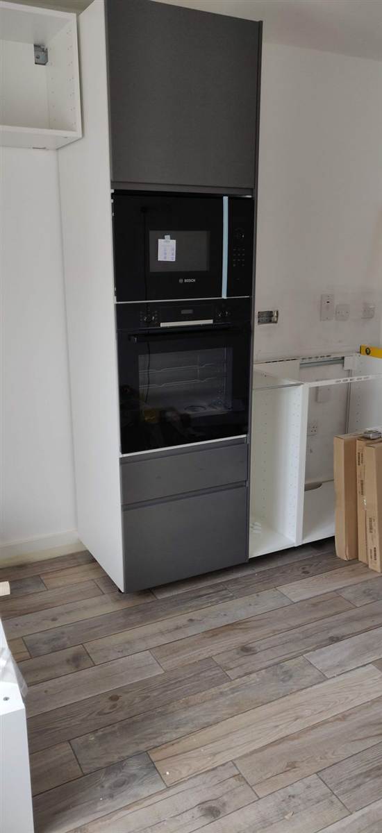 During — tall housing unit fitted with stacked Bosch oven and microwave, grey doors going on